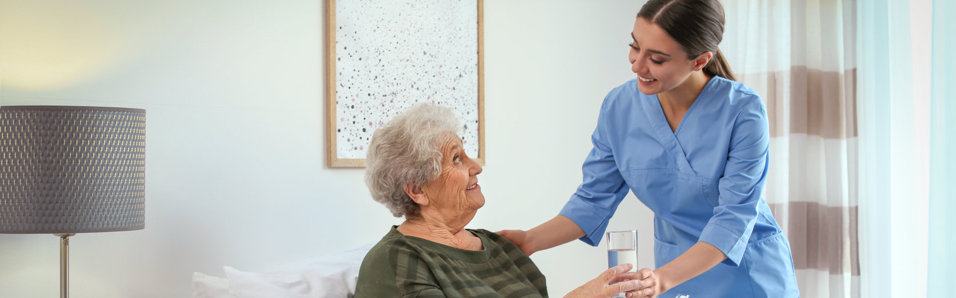 caregiver give her patient a glass of water